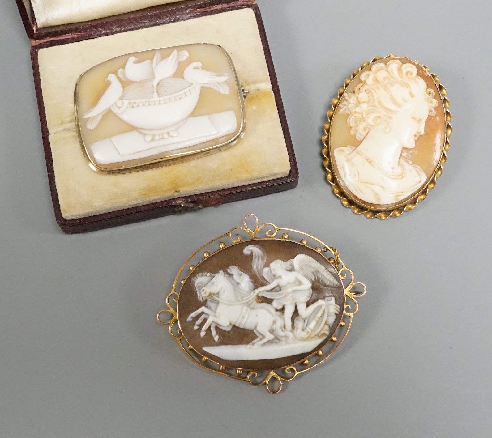 An early 20th century 9ct mounted oval cameo shell brooch, 57mm and two other cameo shell brooches including maiden and pliny doves.